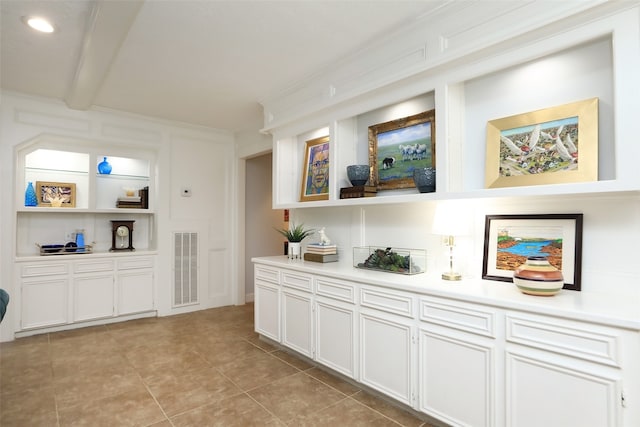 bar with beamed ceiling, built in features, white cabinets, and light tile patterned flooring