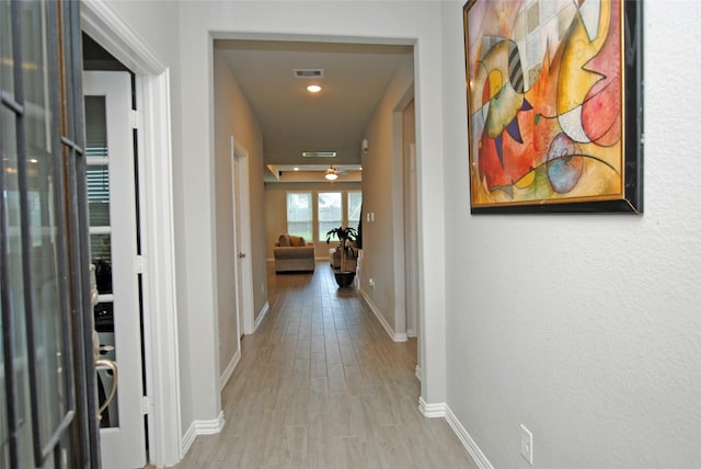 hall with baseboards, visible vents, and wood finished floors