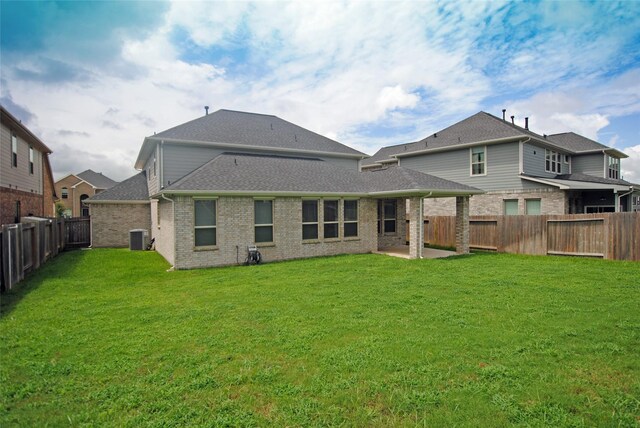 rear view of house featuring central AC unit and a yard