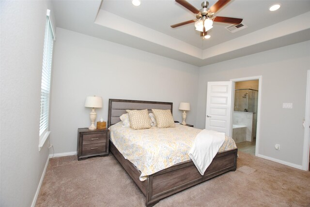 carpeted bedroom with ceiling fan, connected bathroom, and a raised ceiling