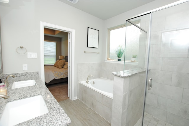 bathroom featuring plus walk in shower, a healthy amount of sunlight, and double vanity