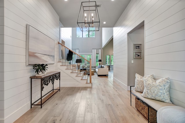 entrance foyer with a notable chandelier, light hardwood / wood-style flooring, and a towering ceiling