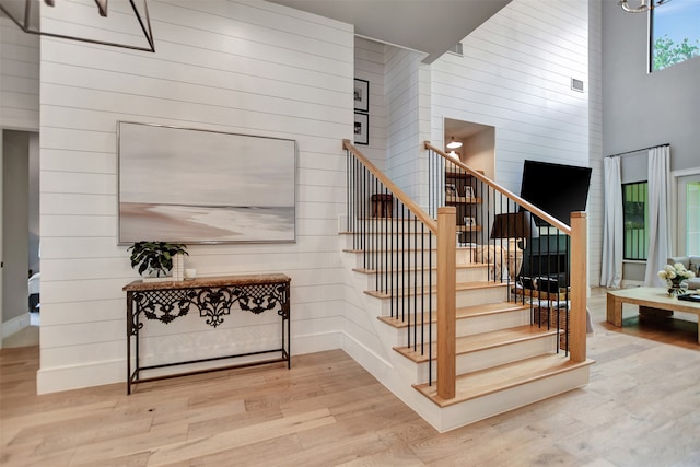 stairway featuring light hardwood / wood-style flooring and a towering ceiling