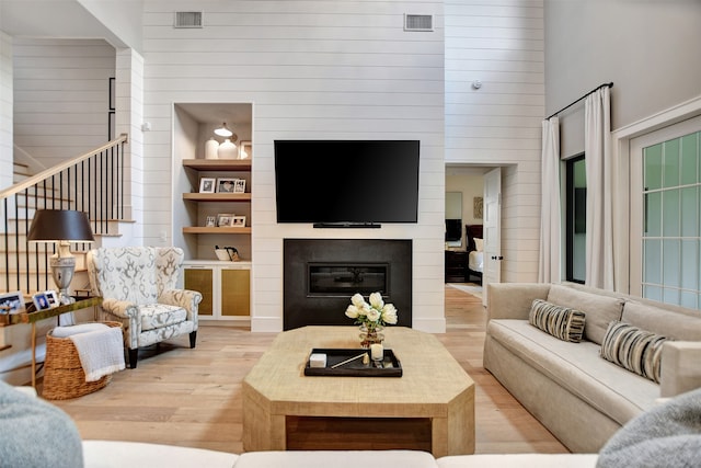 living room featuring built in shelves and light hardwood / wood-style floors