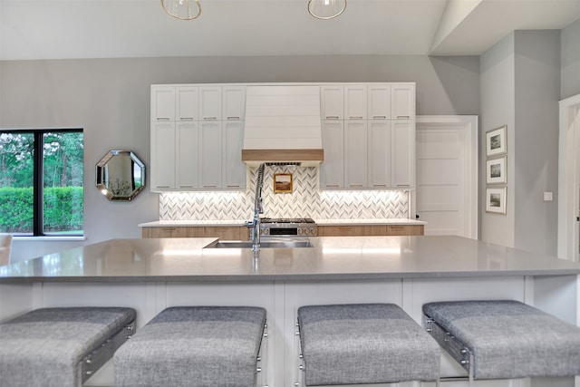 kitchen with vaulted ceiling, an island with sink, a breakfast bar area, and backsplash