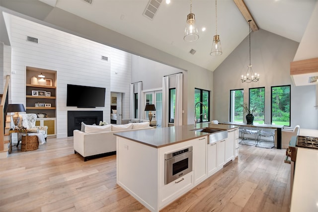 kitchen featuring beamed ceiling, light hardwood / wood-style flooring, a large fireplace, and high vaulted ceiling