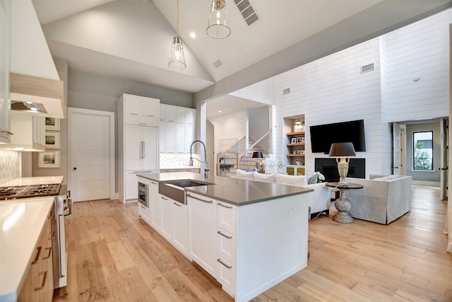 kitchen with white cabinetry, light hardwood / wood-style flooring, and high vaulted ceiling