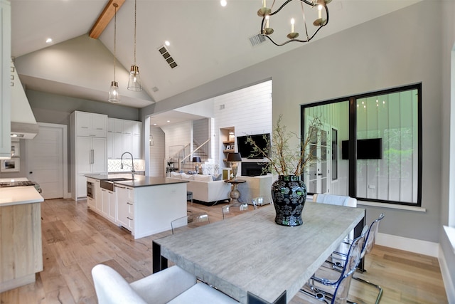 dining room featuring beamed ceiling, a notable chandelier, light hardwood / wood-style flooring, and high vaulted ceiling