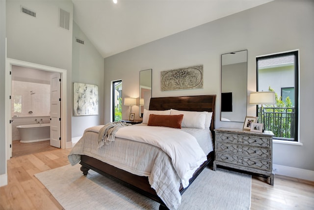 bedroom featuring high vaulted ceiling, connected bathroom, and light wood-type flooring