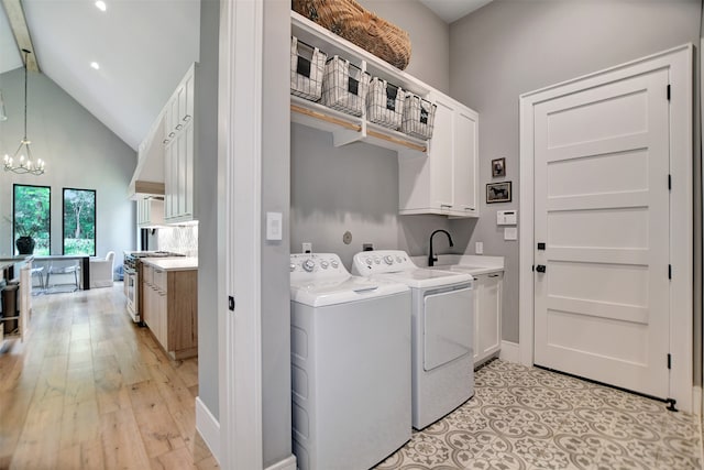 washroom with sink, cabinets, light hardwood / wood-style floors, washer and dryer, and a notable chandelier