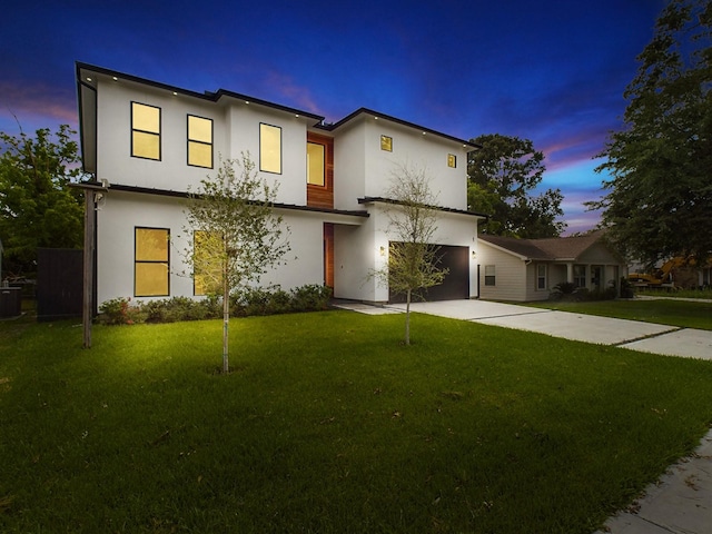 view of front of house with a garage, stucco siding, concrete driveway, and a yard