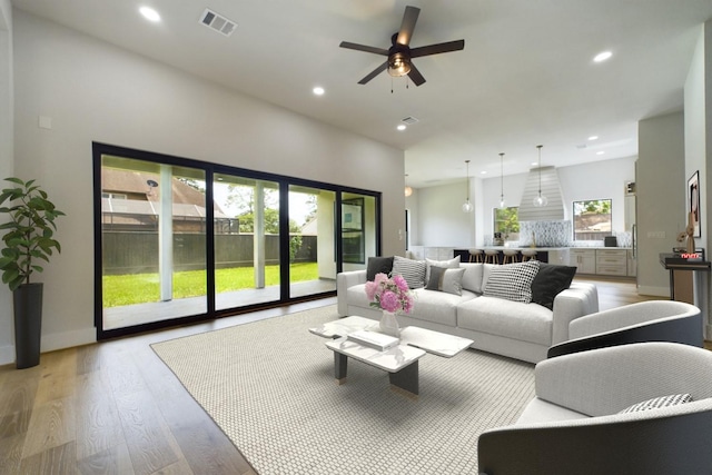 living area featuring baseboards, visible vents, recessed lighting, ceiling fan, and light wood-type flooring