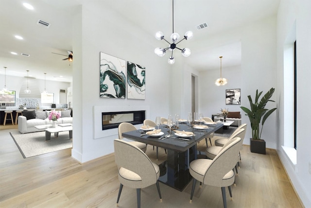 dining area with a glass covered fireplace, recessed lighting, visible vents, and light wood finished floors