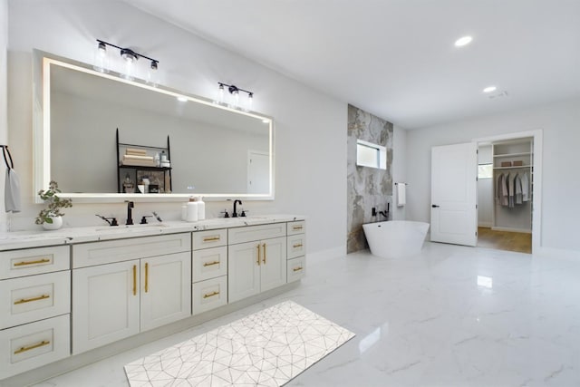 bathroom featuring a freestanding bath, double vanity, marble finish floor, and a sink