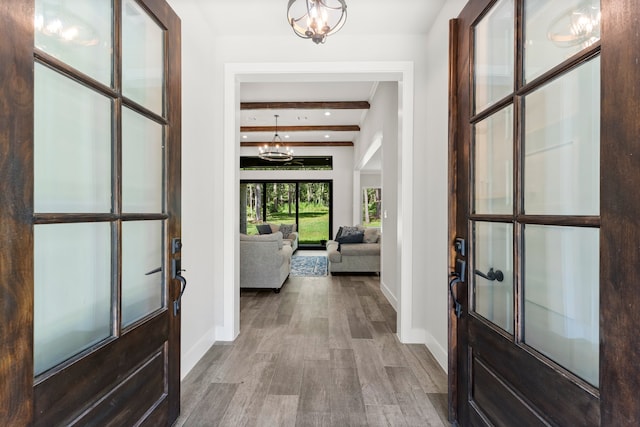 entrance foyer with a notable chandelier, beam ceiling, and hardwood / wood-style flooring