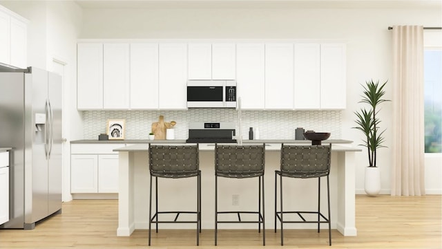 kitchen with a center island with sink, stainless steel refrigerator with ice dispenser, a breakfast bar area, white cabinetry, and light hardwood / wood-style flooring