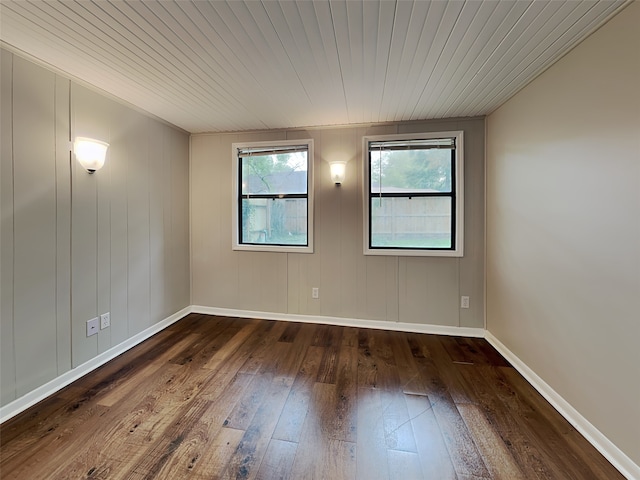 empty room featuring dark hardwood / wood-style flooring and wooden ceiling