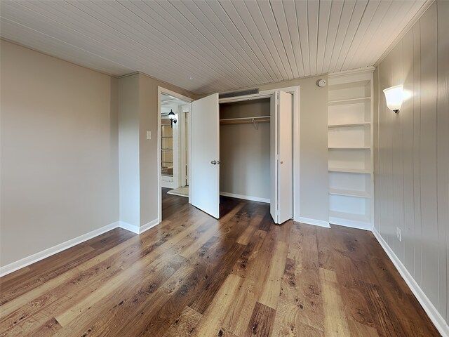 unfurnished bedroom with wood ceiling, a closet, and wood-type flooring