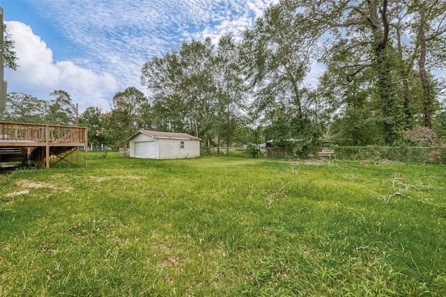 view of yard featuring an outbuilding, a garage, and a wooden deck