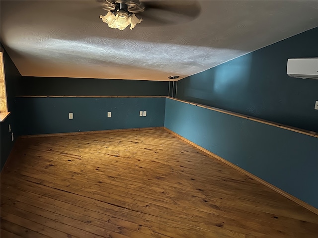 bonus room with lofted ceiling, a wall mounted AC, hardwood / wood-style floors, a textured ceiling, and ceiling fan