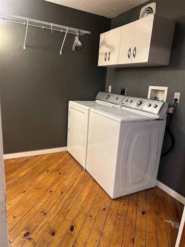 laundry room featuring light hardwood / wood-style flooring, cabinets, and separate washer and dryer