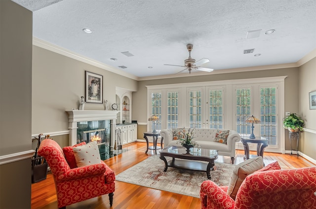 living room featuring a high end fireplace, crown molding, light hardwood / wood-style flooring, and ceiling fan