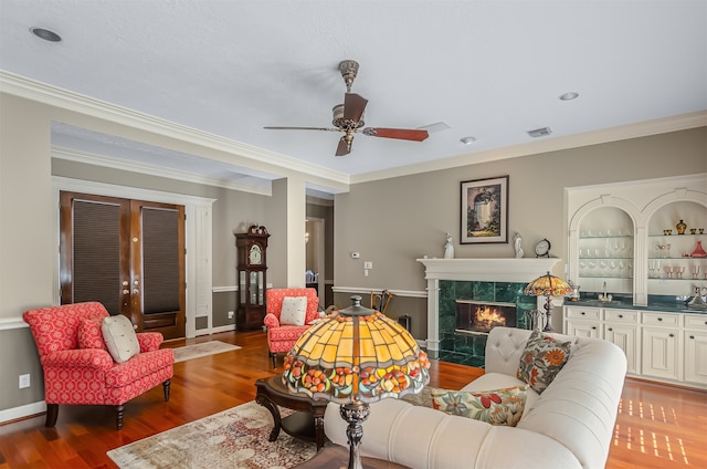 living room featuring ornamental molding, a high end fireplace, ceiling fan, and hardwood / wood-style floors