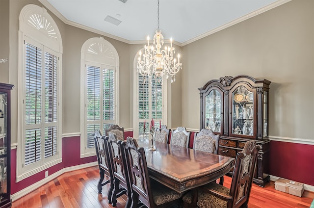 dining space with ornamental molding, hardwood / wood-style flooring, and a chandelier