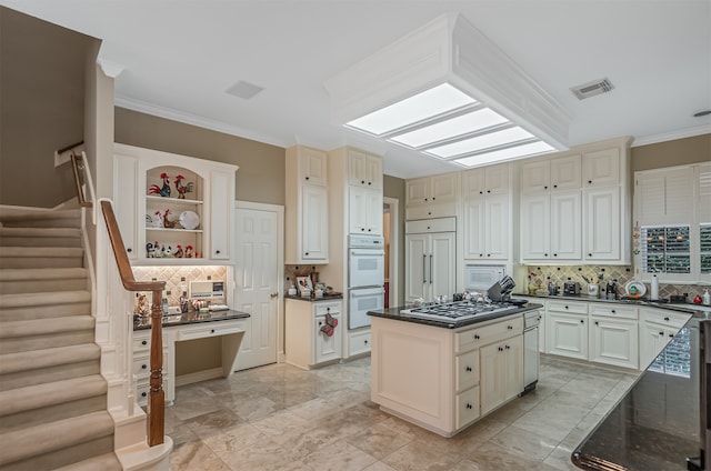 kitchen with dark stone counters, a kitchen island, built in appliances, backsplash, and ornamental molding