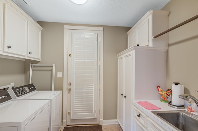 clothes washing area featuring sink, light tile patterned flooring, cabinets, washing machine and dryer, and a textured ceiling