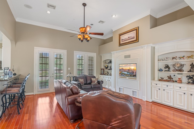 living room with built in features, a high ceiling, ceiling fan, ornamental molding, and hardwood / wood-style flooring