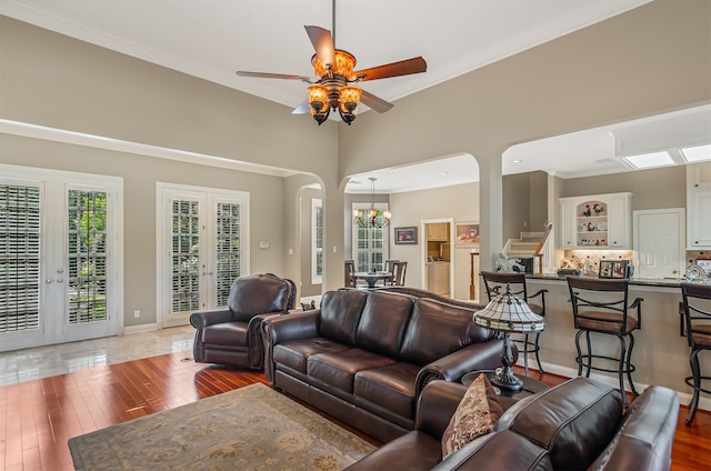 living room with ornamental molding, ceiling fan with notable chandelier, a towering ceiling, and hardwood / wood-style floors