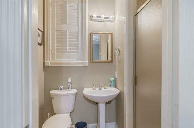 bathroom with sink, a shower with door, and toilet