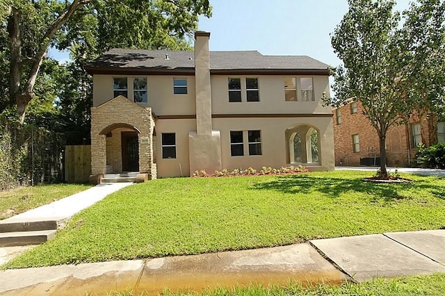 view of front of home featuring a front yard, stucco siding, stone siding, and a chimney