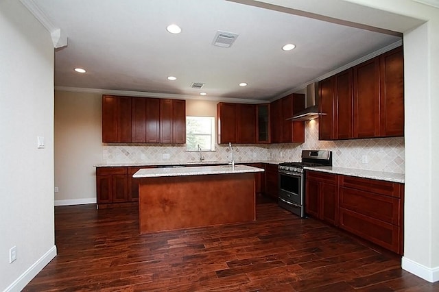 kitchen with wall chimney range hood, dark wood-style floors, crown molding, gas range, and visible vents