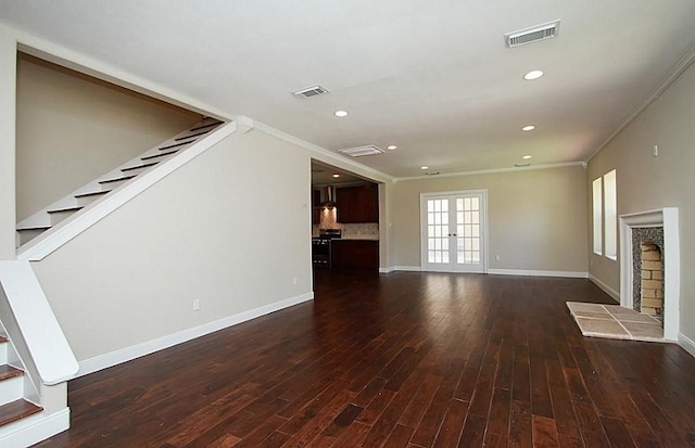unfurnished living room featuring crown molding, dark wood-style floors, visible vents, and stairway