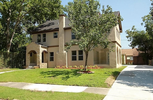 view of front of home with concrete driveway, a front yard, stucco siding, and stone siding