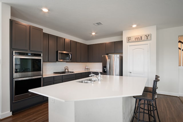 kitchen featuring an island with sink, appliances with stainless steel finishes, sink, and dark brown cabinetry