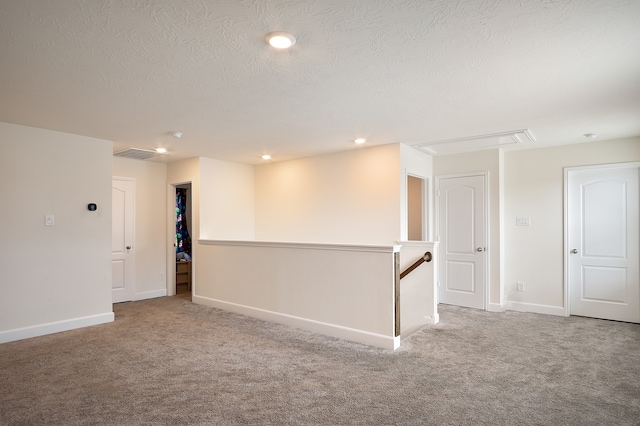 unfurnished room featuring carpet and a textured ceiling