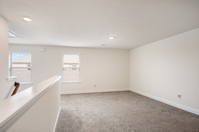 carpeted spare room with a wealth of natural light and a textured ceiling