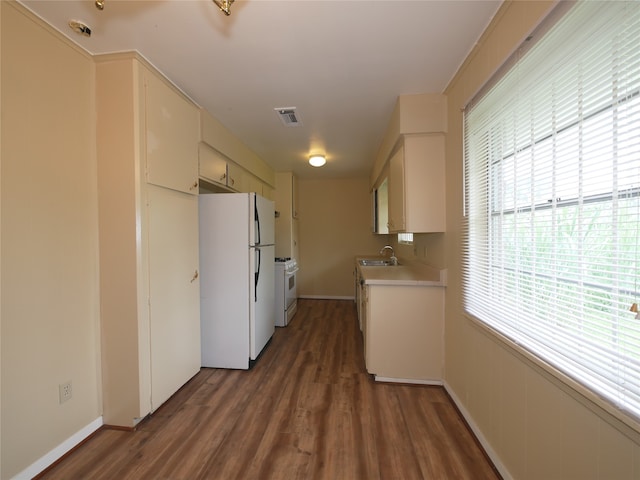 kitchen with dark wood-type flooring, cream cabinetry, white appliances, and sink