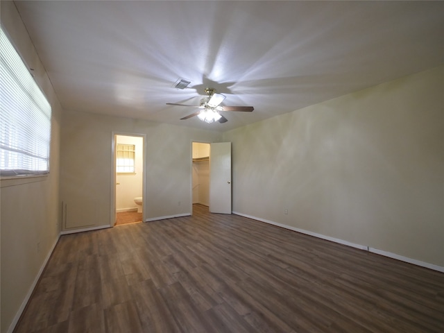 unfurnished bedroom featuring a spacious closet, a closet, ceiling fan, dark hardwood / wood-style floors, and ensuite bathroom