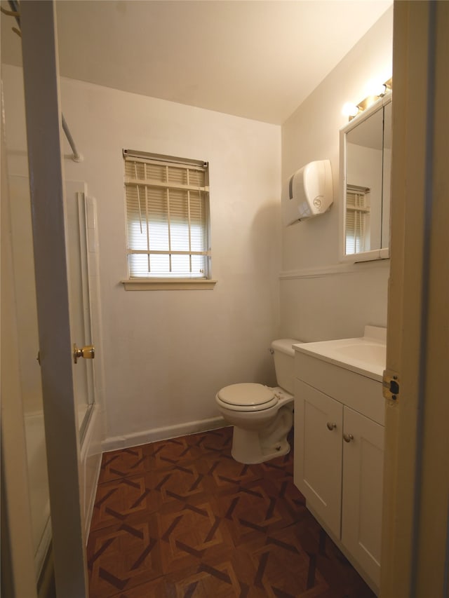 bathroom with vanity, toilet, and parquet flooring