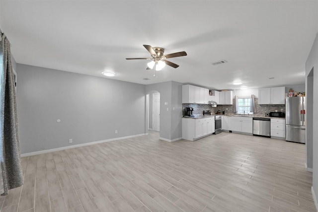 kitchen featuring tasteful backsplash, appliances with stainless steel finishes, ceiling fan, light hardwood / wood-style floors, and white cabinets