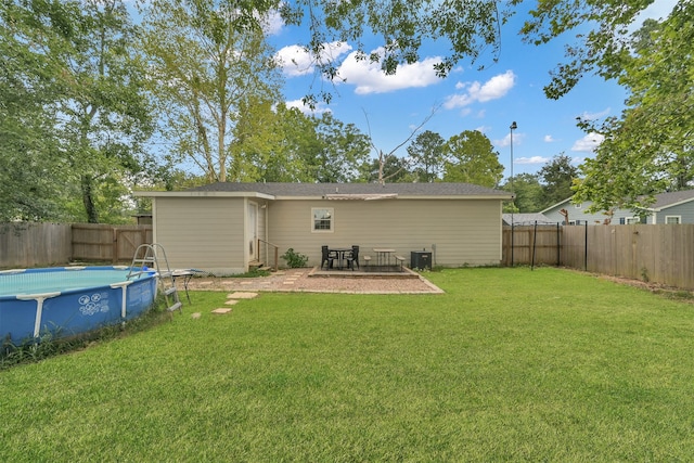 back of property featuring central AC, a fenced in pool, and a lawn