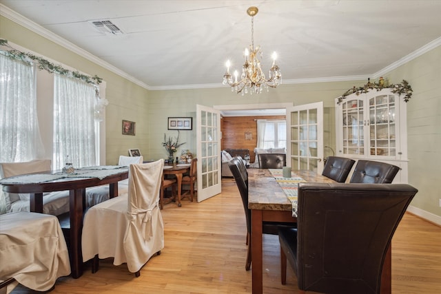 dining area featuring light hardwood / wood-style floors, crown molding, and a chandelier