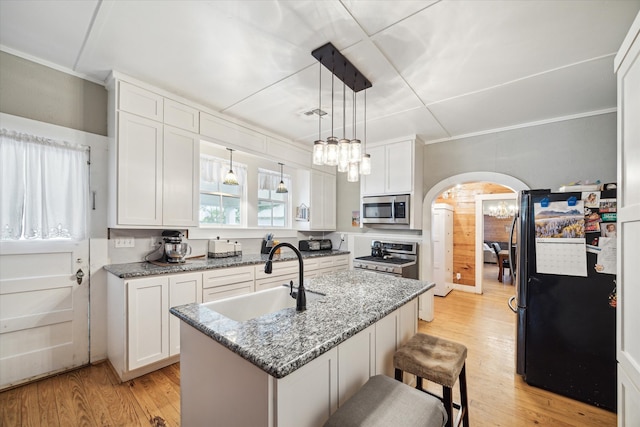 kitchen featuring light wood-type flooring, white cabinets, a kitchen island with sink, stainless steel appliances, and sink