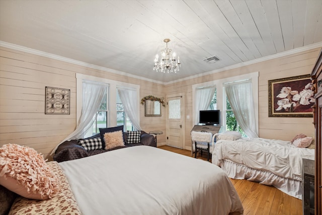 bedroom with ornamental molding, hardwood / wood-style floors, and a chandelier