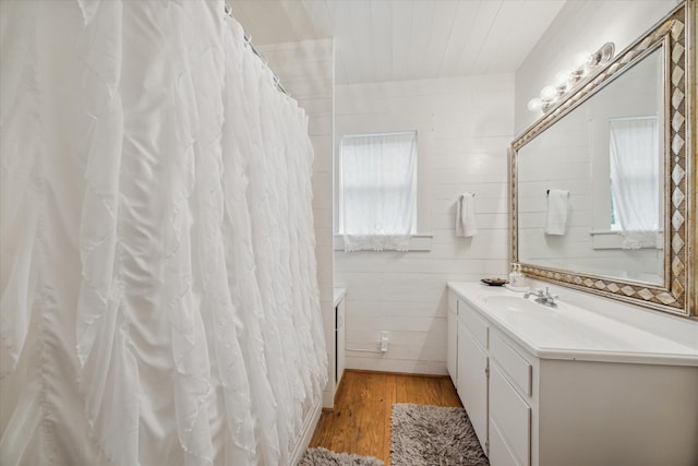 bathroom featuring vanity, a wealth of natural light, wood-type flooring, and tile walls