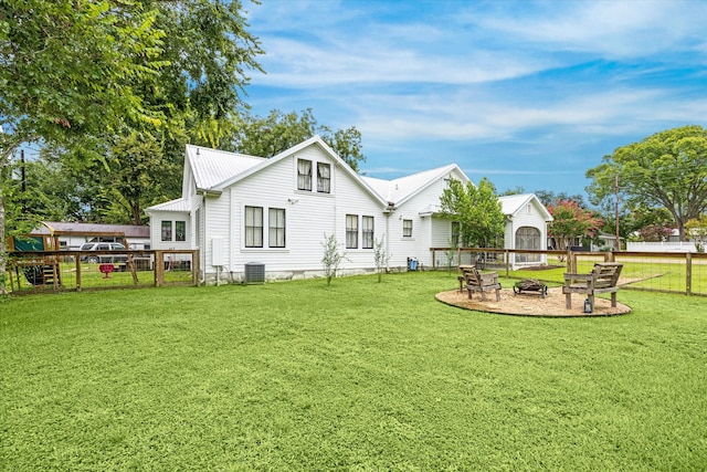 back of house featuring cooling unit, a lawn, and an outdoor fire pit